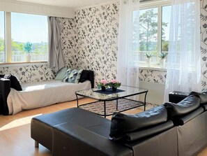 A modern living room with a sofa, a glass coffee table, and a view of the outdoors through large windows. - 4 Star Holiday Home in Uddevalla (Uddevalla)
