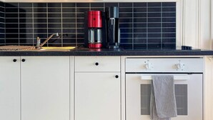 A kitchen with white cabinets, a black countertop, a red coffee maker, and a stainless steel oven. - 4 Star Holiday Home in Uddevalla (Uddevalla)