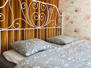 A bed with a metal headboard, patterned bedding, and pillows.