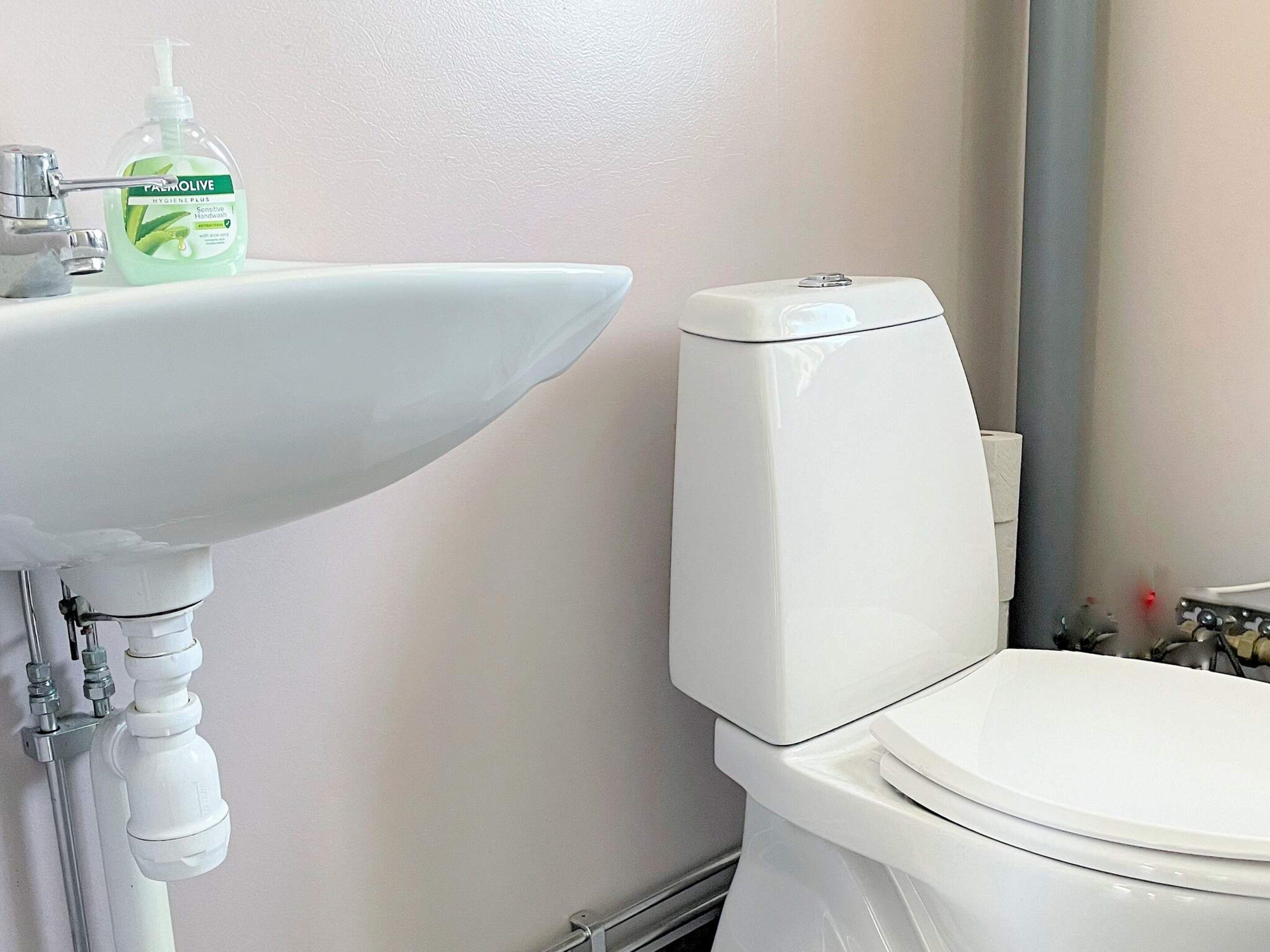 A bathroom with a white sink, toilet, and a mirror.
