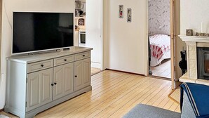 A room with a television on a cabinet, a fireplace, and a bed with a floral bedspread. - 5 Star Holiday Home in Nynashamn (Nynashamn)
