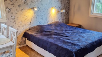 A bedroom with a bed, two wall-mounted lamps, a chair, and a window.