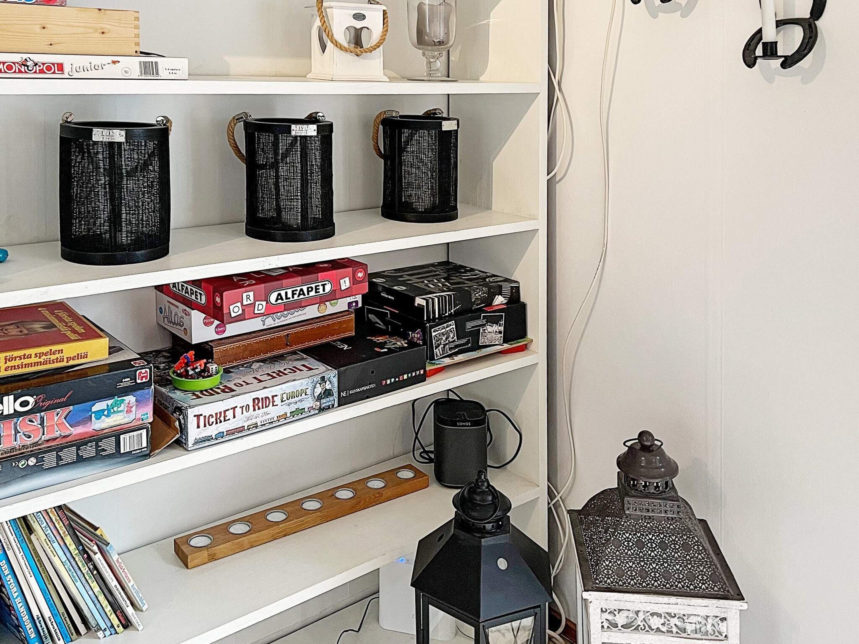 Une bibliothèque contenant divers jeux de société, une machine à café et une lanterne décorative.