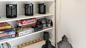 Une bibliothèque contenant divers jeux de société, une machine à café et une lanterne décorative.