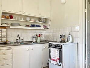Une cuisine avec des meubles blancs, une cuisinière et une machine à café.
