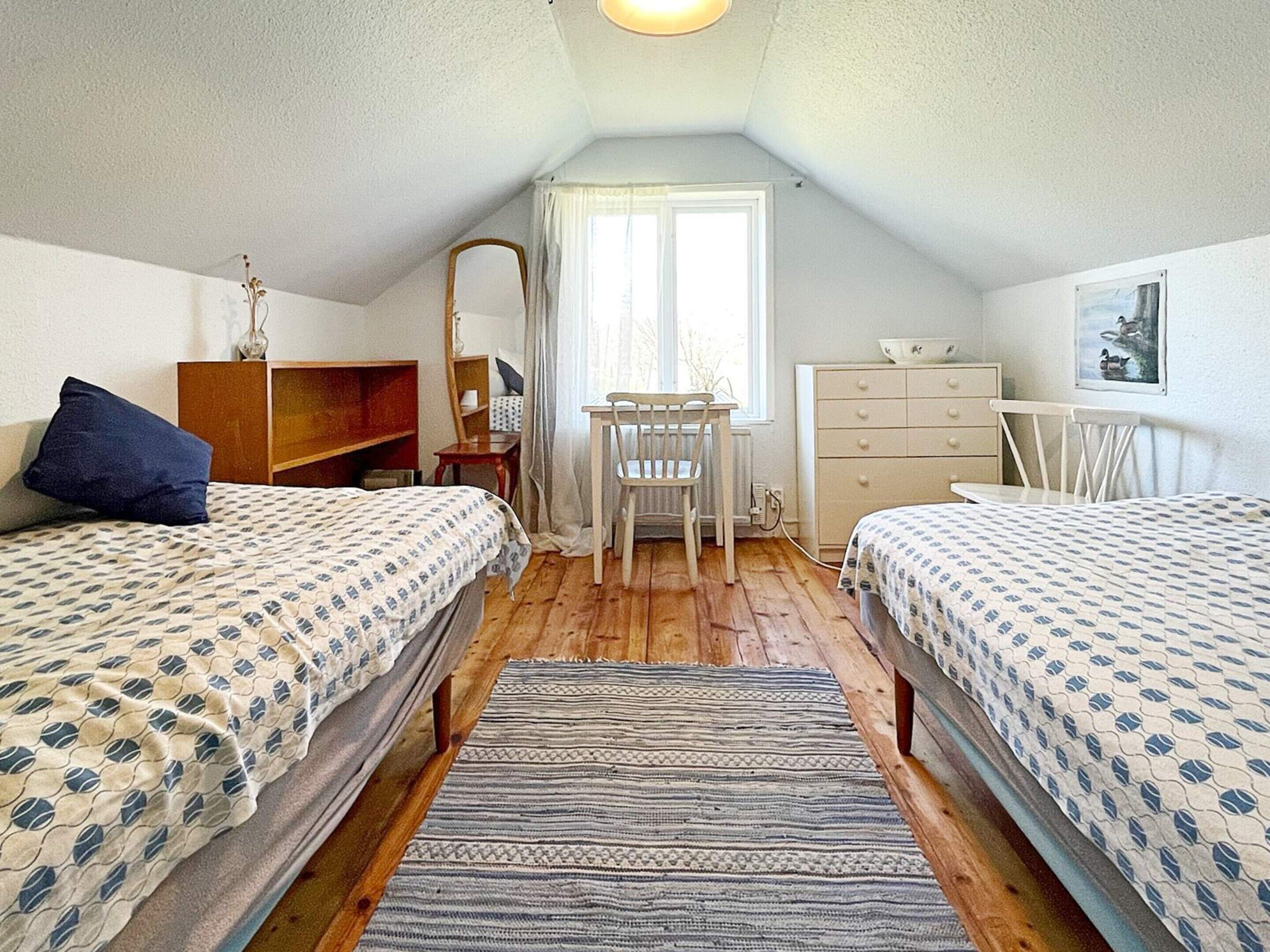 Une petite chambre confortable avec deux lits, un bureau et une commode.