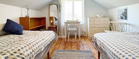 Une petite chambre confortable avec deux lits, un bureau et une commode.