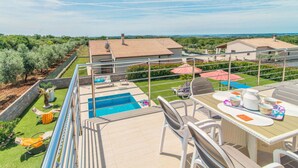 Terraza en la azotea con piscina, mobiliario exterior y vistas del paisaje circundante.