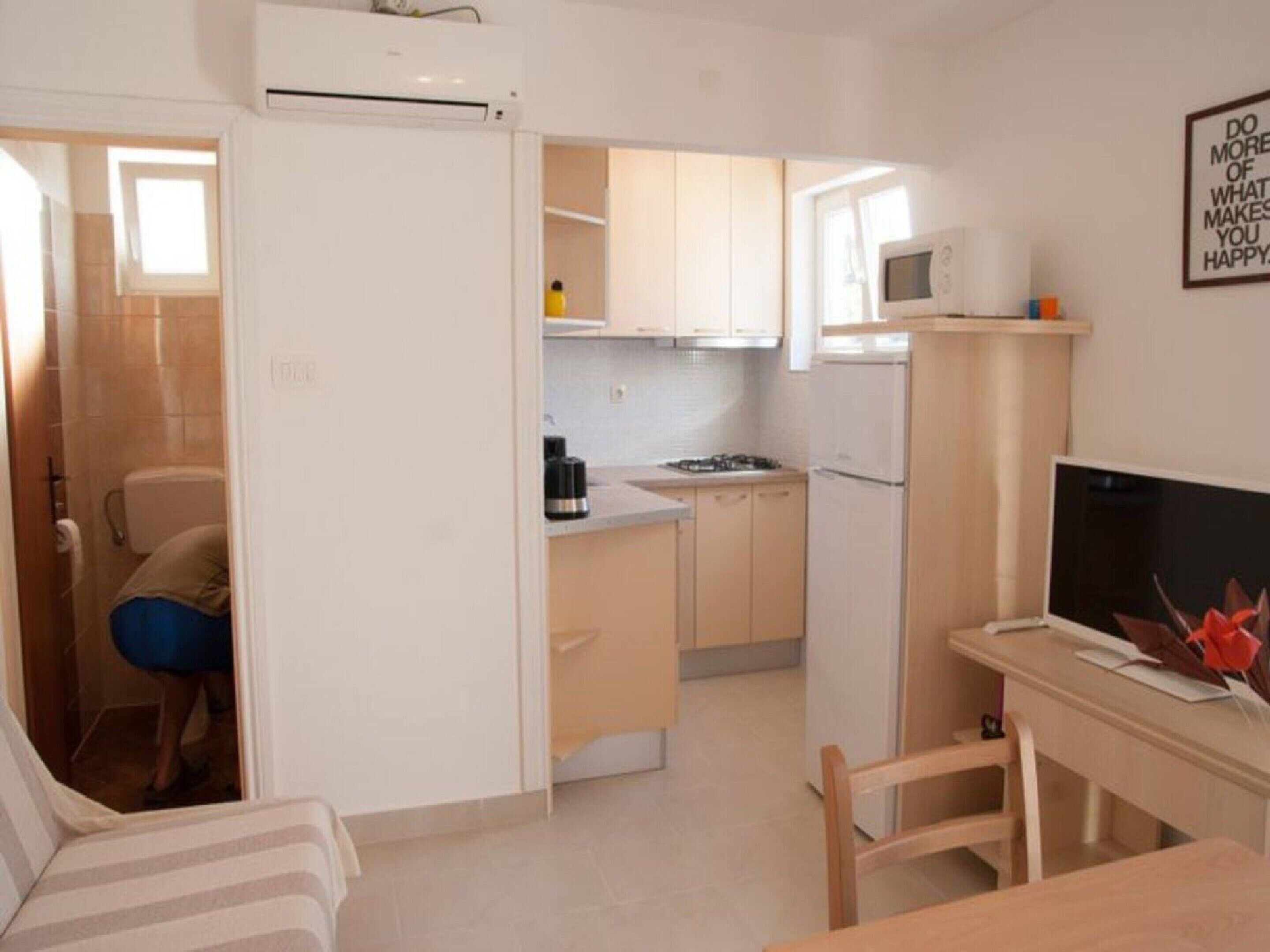 Cocina compacta con refrigerador, microondas y estufa. Hay un comedor con mesa y sillas.