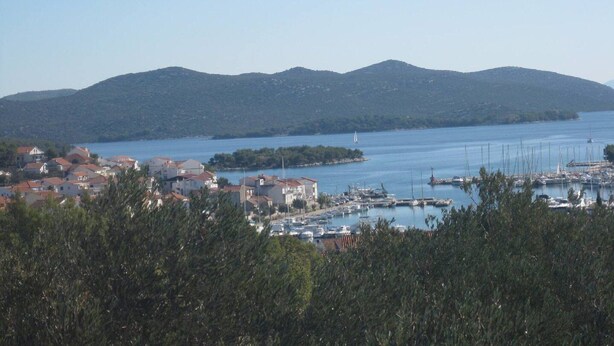 A coastal town with a marina, houses with red roofs, and a hilly backdrop. - Apartments Paula - One Bedroom Apartment With Terrace 1 (Tisno)