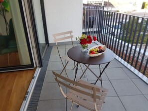 A balcony with a table set for two, a vase with flowers, and a bowl of fruit. - Santis Comfortable Holiday Residence (Friedrichshafen)