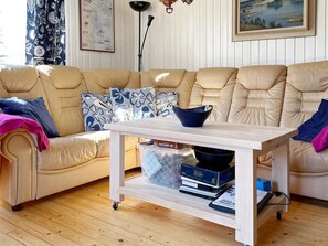 A living room with a beige sofa, a white coffee table with books, and a blue bowl. - 4 Person Holiday Home in Gusum (Valdemarsvik)