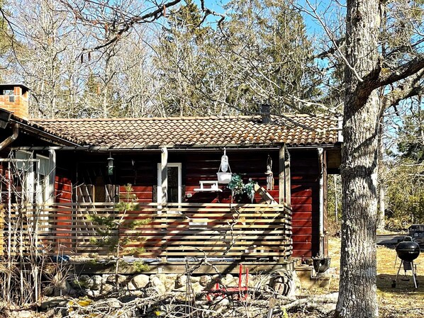 A rustic cabin with a tiled roof, wooden porch, and a small garden area. - 4 Person Holiday Home in Gusum (Valdemarsvik)