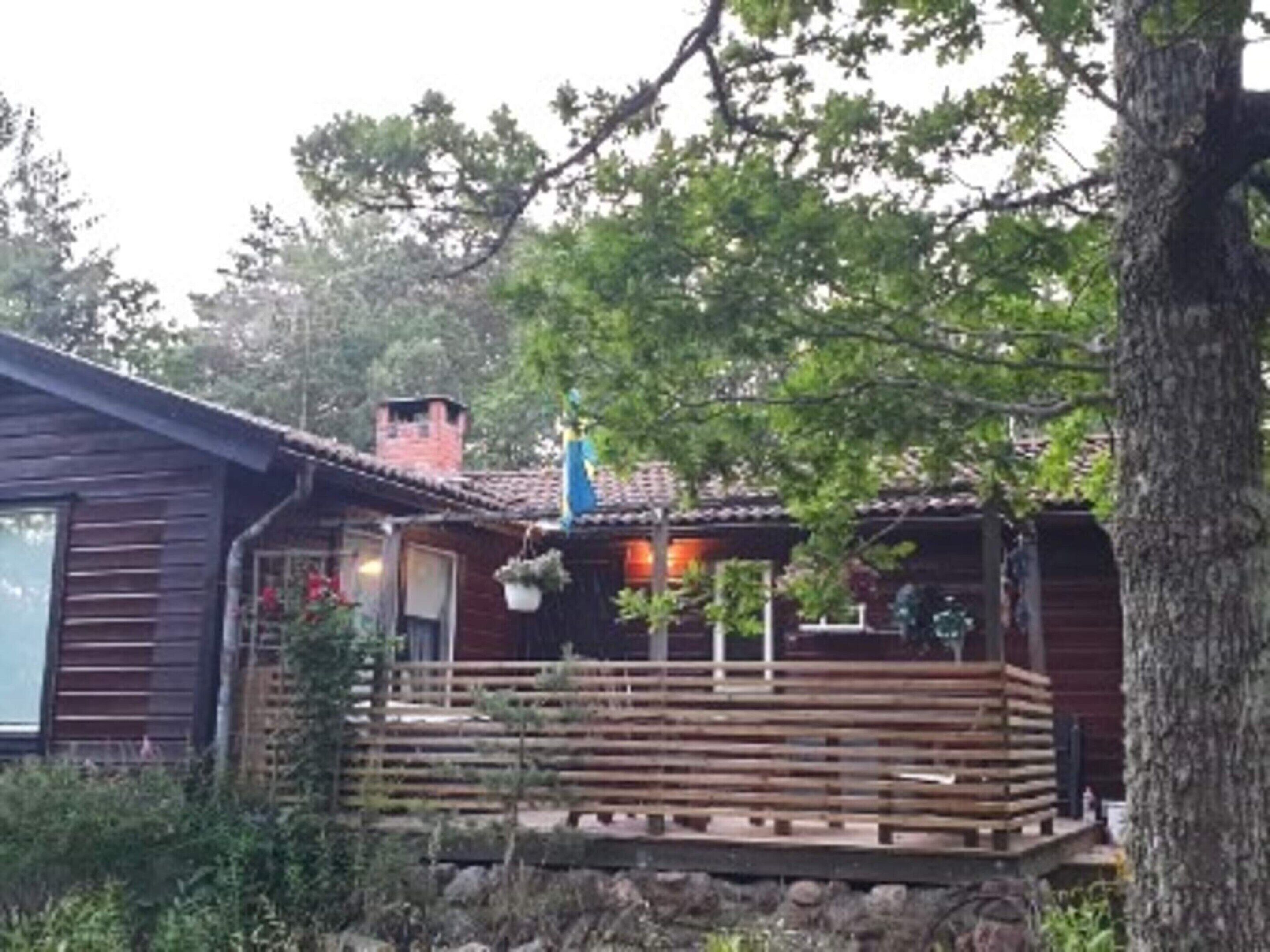 A wooden cabin with a porch, surrounded by trees.