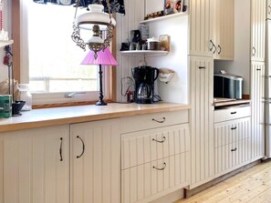 A kitchen with white cabinets, a coffee maker, and a window with a lamp. - 4 Person Holiday Home in Gusum (Valdemarsvik)