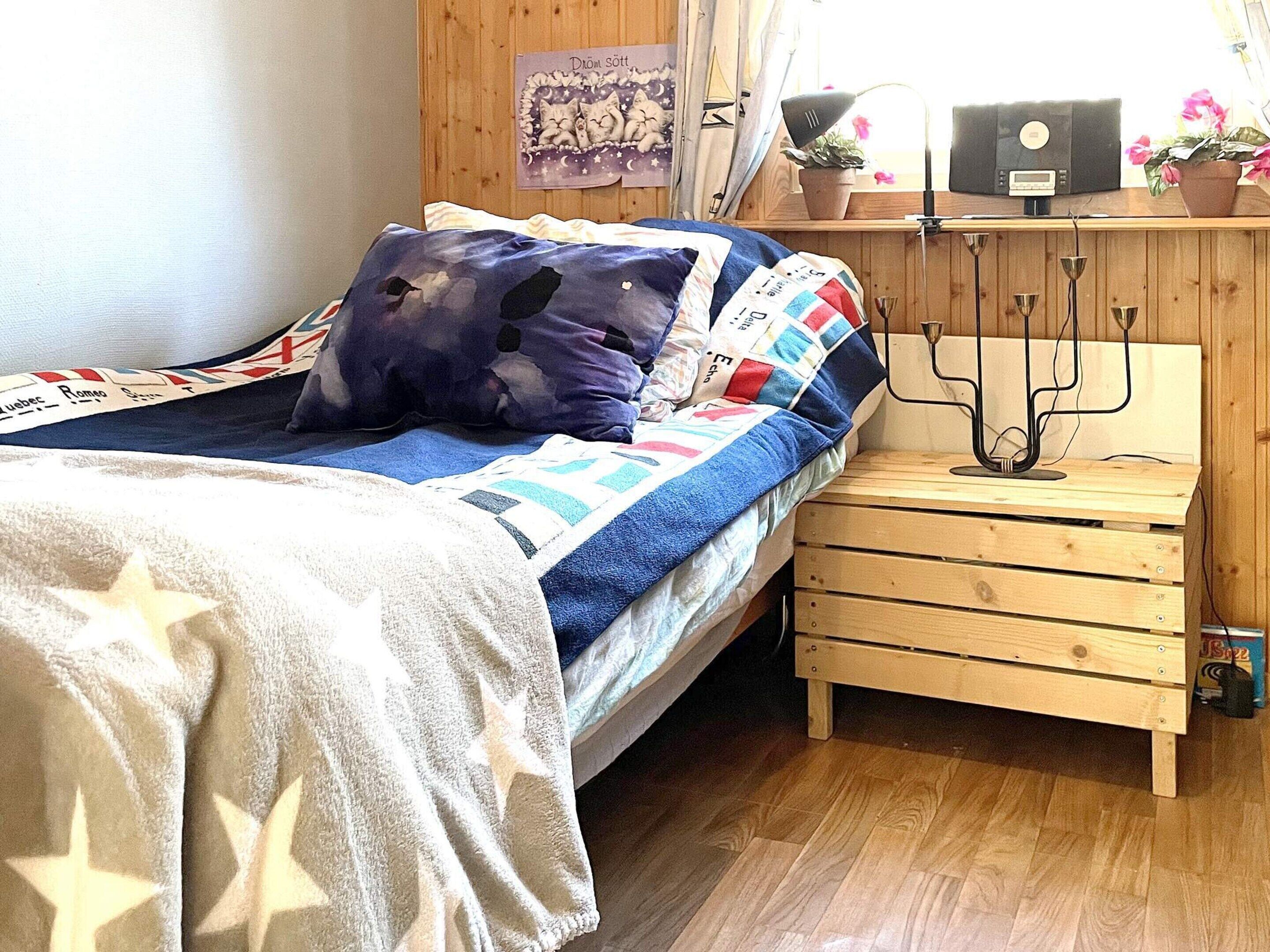 A bed with a quilt, pillows, and a bedside table with a lamp.