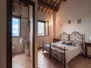 Une chambre à coucher comprenant un lit, une fenêtre, un radiateur et une porte donnant sur une salle de bain.