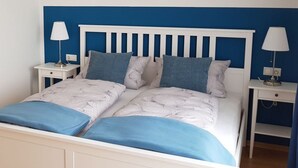 A double bed with a white headboard and blue bedding, flanked by two bedside tables with lamps, in a room with blue walls. - Palatinate Forest Comfortable Holiday Residence (Silz)