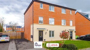 A multi-story residential building with a brick facade, a flat roof, and a small front garden. - Spacious 5BR Chester | Group & Contractor Stays (Cheshire West and Chester)