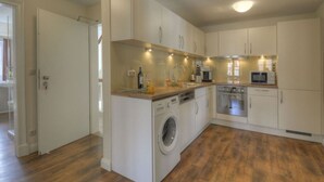 A compact kitchen with a washing machine, a microwave, and a coffee maker. - Riechey Comfortable Holiday Residence (Fehmarn)