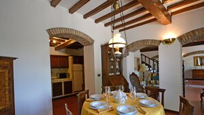A dining area with a yellow tablecloth, wooden chairs, and a chandelier.