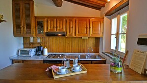 A kitchen with wooden cabinets, a brick countertop, a stove, a sink, and a window.