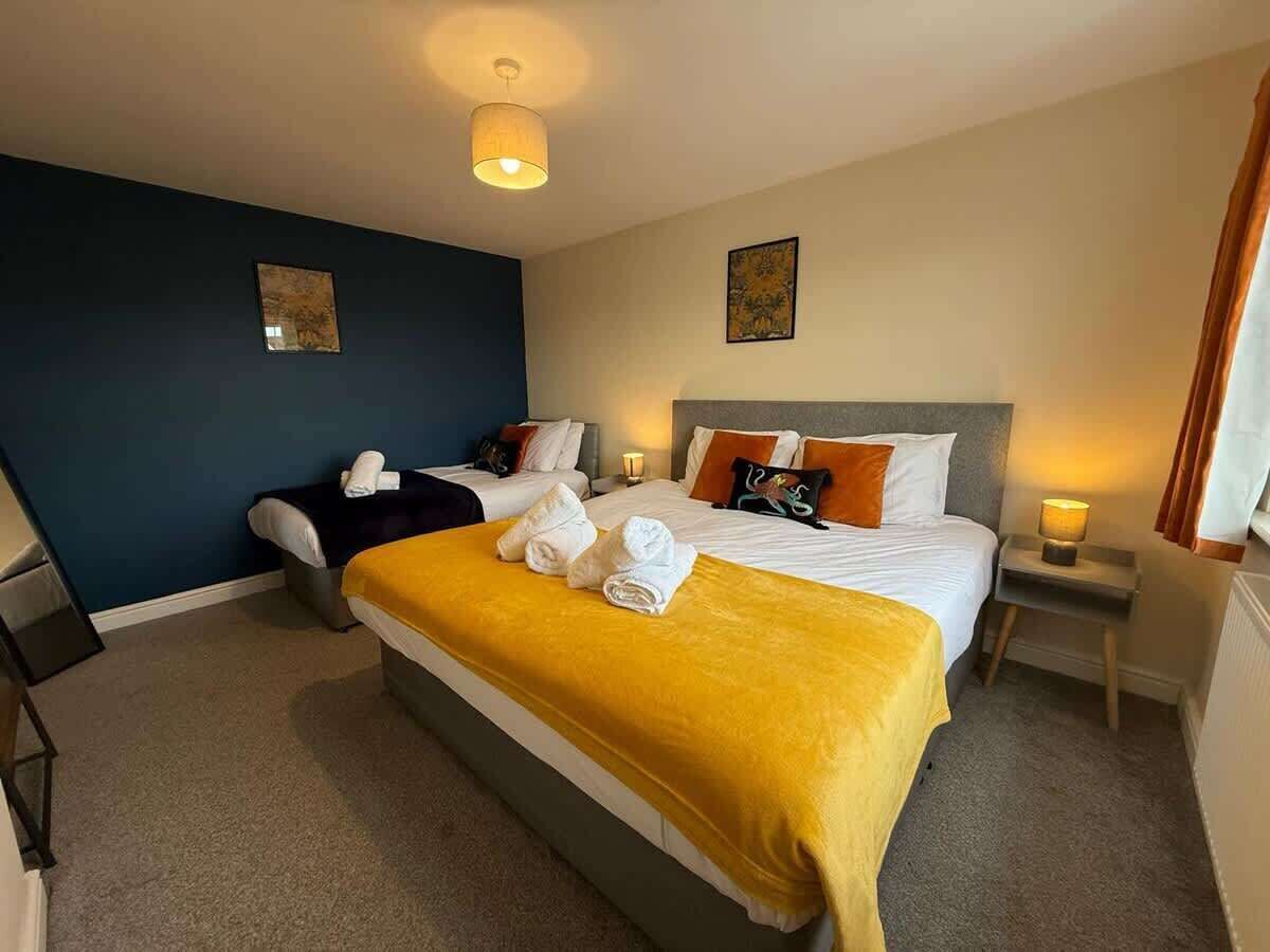 Ein Hotelzimmer mit einem großen Bett, einem kleineren Bett, einem Schreibtisch und einem Sessel.