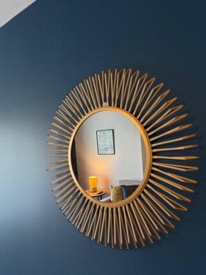 A round mirror with a sunburst frame on a dark wall.