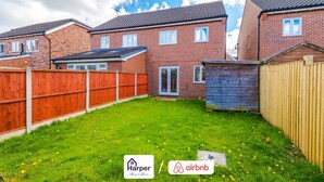 A residential area with brick houses, a grassy yard, and a wooden fence. - Cosy 3BR Deeside Sleeps 5 | Contractor Stays (Flintshire)
