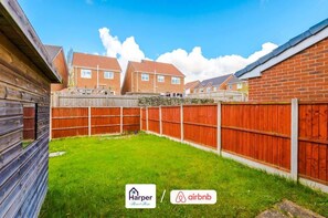 A residential area with a fenced backyard, brick houses, and logos for Harper Home and Airbnb. - Cosy 3BR Deeside Sleeps 5 | Contractor Stays (Flintshire)