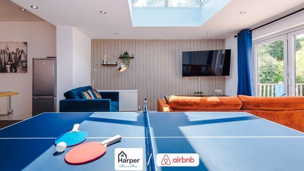 A modern living room with a ping pong table, a flat-screen TV, and a cozy seating area. - 4BR Home | Sleeps 10 | 7 Beds for Family & Crew (Flintshire)