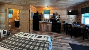 Een hutje met een bed, een kitchenette, een eethoek en een badkamer.