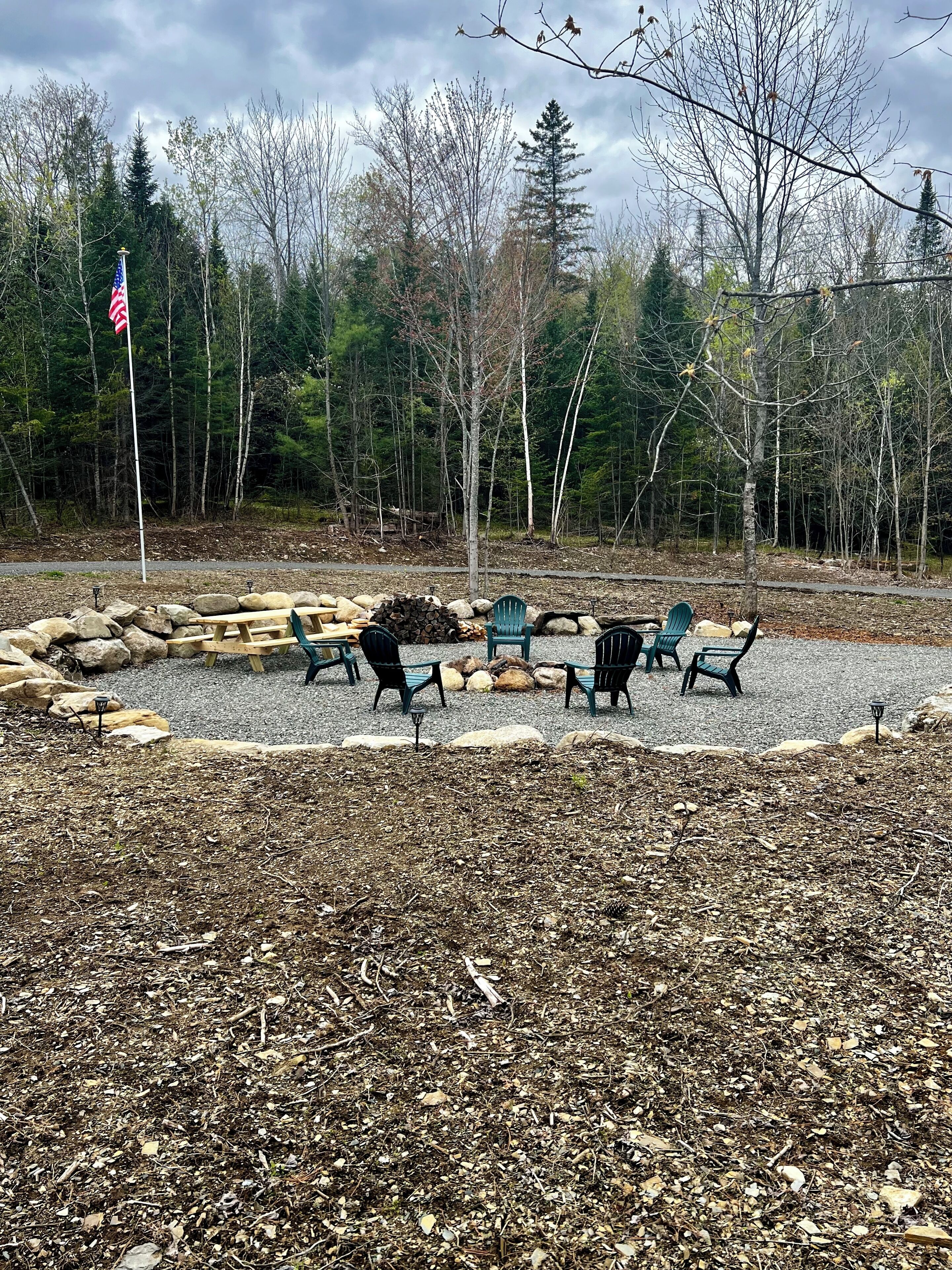 Un parc avec des bancs, un drapeau et une forêt en arrière-plan.