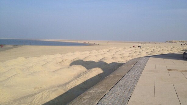 A sandy beach with a paved walkway and a calm sea in the background. - Holiday Apartment Susewind (Borkum)