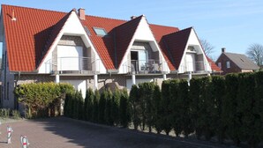 A row of three houses with red roofs and white walls, each with a balcony. - Holiday Apartment Susewind (Borkum)
