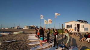 A beachside paddleboarding class with participants standing on boards, a lifeguard station, and a small building labeled "Lifeguard Station." - A in Haus Seewind Comfortable Vacation Home (Wittduen)