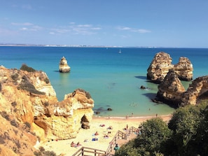 Une plage côtière bordée de formations rocheuses et offrant une vue dégagée sur la mer.