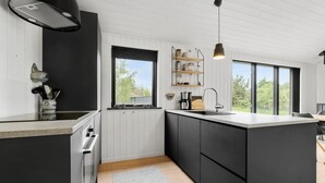 A modern kitchen with white cabinetry, a large island, a built-in oven, and a window overlooking greenery. - 3 bedroom nice home in Store Fuglede (Store Fuglede)