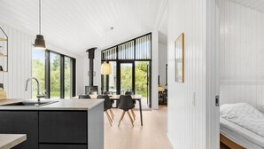 A modern kitchen with a central island, a dining area with a table and chairs, and a bedroom with a bed. - 3 bedroom nice home in Store Fuglede (Store Fuglede)