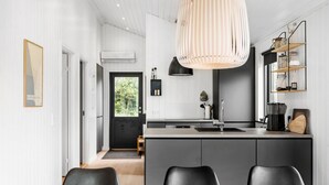 A modern kitchen with a central island, black chairs, and a hanging light fixture. - 3 bedroom nice home in Store Fuglede (Store Fuglede)