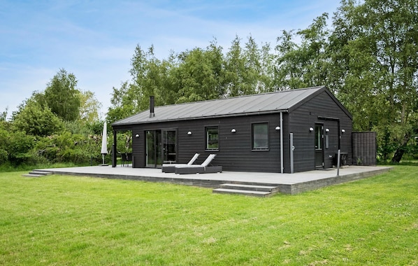 Relax in a serene setting surrounded by lush greenery, with a covered patio area perfect for unwinding.