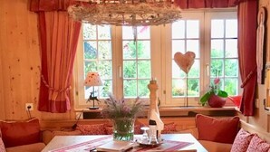 Um quarto acolhedor com decoração em madeira, uma mesa de jantar com um vaso de flores e um enfeite em formato de coração no parapeito da janela.