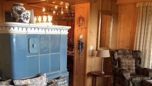 Uma sala de estar acolhedora com um armário azul, almofadas estampadas, uma poltrona xadrez e uma pequena mesa com abajur.