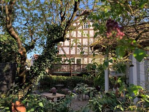 Ein Innenhof mit Tisch und Stühlen, umgeben von Grünflächen und einem Gebäude mit Balkon.