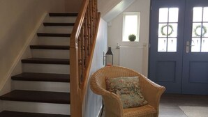 A staircase with dark steps and a wooden handrail, leading to a door with a wreath. - Werts HOF Holiday Home (Rauschenberg)