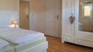 A bedroom with a bed, a wardrobe, and a door leading to another room. - Werts HOF Holiday Home (Rauschenberg)