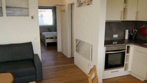 Un ambiente compatto con angolo cottura, zona pranzo e camera da letto.