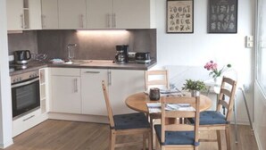 Una cucina moderna con mobili bianchi, un tavolo da pranzo con sedie e una macchina per caffè.