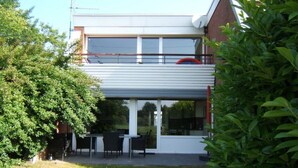 Una casa moderna a due piani con un portico coperto e arredi da esterno.