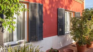 A building with a red facade, black shutters, and potted plants. - Belvilla by OYO Villa Valencina de la Concepcion (Valencina de la Concepcion)